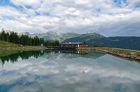 Bergeralm (de), avec sa réserve d'eau pour les canons à neige et un restaurant à l'arrière plan, à Steinach am Brenner. Aout 2021.