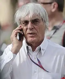 Photo de Bernie Ecclestone, chemise et cheveux blancs, téléphonant