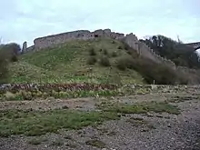 Un mur de pierre en ruine sur un monticule herbeux