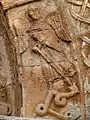 Saint Michel debout, ailes repliées, portant un bouclier, tient une lance qu'il a enfoncé dans la gueule du dragon.