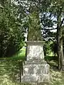 Monument aux morts, stèle sous des arbres.