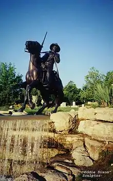 Une photographie de couleur du monument des Buffalo Soldier à Fort Leavenworth, Kansas. La sculpture a été réalisée par Eddie Dixon et se trouve au sommet d'une cascade. Il est composé d'un cavalier monté sur un cheval au galop