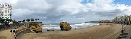 Plage de sable sur laquelle se trouve un grand rocher.