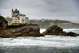 Vue d'une villa perchée sur un rocher surplombant la mer.
