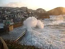 Des lames se brisant sur les digues d'un village de bord de mer.