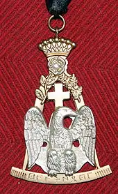 Photo en couleur d'un bijou maçonnique : on voit un aigle d'argent sur fond or surmonté d'une couronne et d'une croix