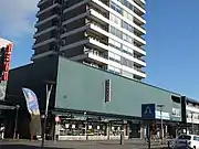 Photographie en couleurs d'un bâtiment commercial surmonté d'une tour d'immemble.