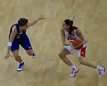 Sue Bird, le ballon dans les mains, opposée à Céline Dumerc, qui tente d'intercepter une passe les bras écartés.