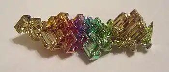 Masse cristallisée fortement colorée de bismuth oxydé en surface.