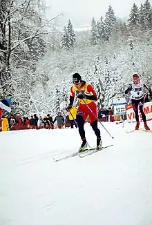 Deux skieuses de fond, l'une derrière l'autre, en haut d'une montée.