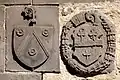 Blasons sculptés en pierre de Volvic de l'abbé Marcenat (à gauche) et des abbés Duprat (à droite) au-dessus d'une porte murée entre le bas-côté sud de l'église et le cloître.