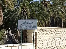Panneau bilingue devant des palmiers.
