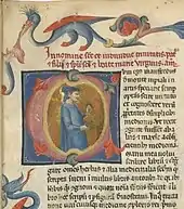 Détail d'une page de manuscrit montrant un texte dont les deux premières lignes, à l'encre rouge, sont suivies d'une lettrine C enluminée contenant une figure de médecin en tunique bleue, et borduré de motifs d'animaux et de végétaux.