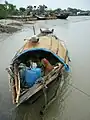 Pêcheur bangladais se reposant à l'ombre d'un sampan à Barishal.