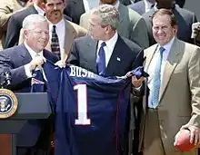 Trois hommes tenant un maillot de football américain.