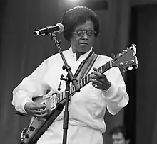 Photographie en noir et blanc d'un homme noir jouant de la guitare.