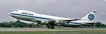 Photo d'un avion de Pan Am au décollage vu de la gauche. Les roues avant ont quitté le sol tandis que le train d'atterrissage principal est toujours en contact avec la piste.