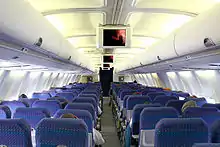Intérieur d'un avion. Des rangées de trois sièges se trouvent autour d'un couloir central.