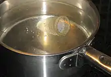 Une coupe menstruelle transparente plongée dans une casserole d'eau bouillante.