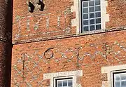 Détail de la date de construction du donjon écrite en briques vernissées et en chiffes en fer forgé.