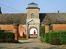 Photo couleur de l'entrée de l'ancienne basse-cour de l'abbaye construite de 1766 à 1767, avec son portail datant du XVIIe siècle.