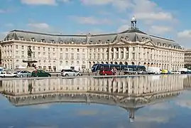 Vue d'ensemble du palais de la Bourse avec son reflet dans le miroir d'eau de la place de la Bourse.