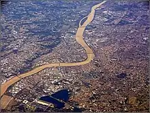 Vue très large de Bordeaux. On aperçoit les deux rives de la ville et la Garonne la traversant en formant une courbe.