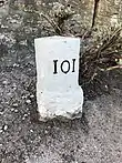 Photographie en couleurs d'un petit bloc blanc pierreux parallélépipédique avec l'inscription 101 sur un côté.