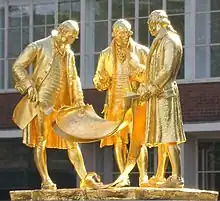 Statues dorées de trois hommes.