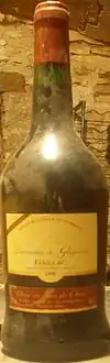 La photo couleur représente une bouteille couverte de poussière révélant don vieillissement.