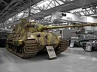 Un Tigre II camouflé, exposé au musée des blindés de Bovington. Le canon surplombe la proue du char de plusieurs mètres.