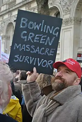 Manifestant brandissant une pancarte où il affirme ironiquement avoir survécu au massacre de Bowling Green.