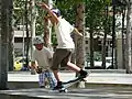 Un jeune skater effectue un manual, il roule en équilibre sur les roues arrières de son skateboard et maintient l'équilibre avec ses bras.