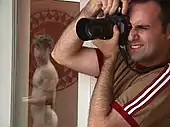 Photo d'un photographe en activité tenant un appareil photo verticalement sur son œil droit.