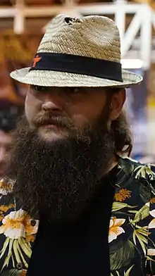 Bray Wyatt avec une longue barbe noire et un chapeau de paille