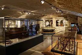 Salle d'un musée installé dans un vieux château. Des maquettes sont visibles.