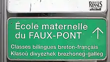 Panneau de signalisation routière, indiquant : « École maternelle du Faux-Pont, classes bilingues breton-français, Klasoù divyezhek brezhoneg-galleg ».