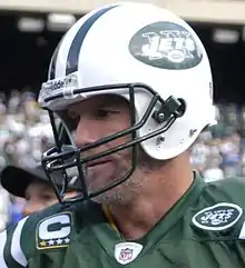 Portrait en tenue vert et blanc de joueur, avec le casque de football américain.