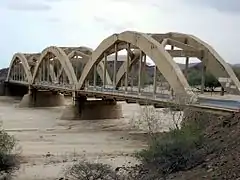 Pont en béton de trois travées traversant une rivière.