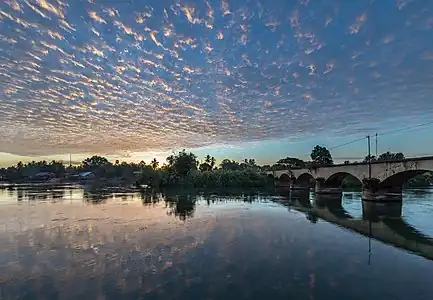 Pont vers Don Khon vu depuis Don Det avec le reflet dans l'eau du Mékong de nuages orange filandreux au lever du soleil, à Si Phan Don, Laos. janvier 2022