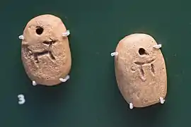 Deux petites tablettes d'argile avec des pictogrammes représentant des animaux et un signe rond.
