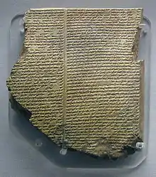 Tablette d'argile accrochée à un mur et recouverte de caractères cunéiformes.