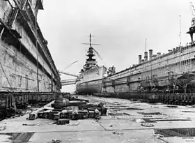 Photographie d'un grand navire de guerre prise depuis le fond de la cale sèche.