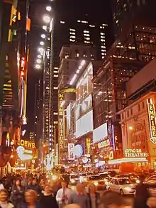 Grand boulevard de nuit avec des personnes et des voitures.