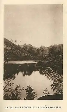 Vieille photo noir et blanc montrant un lac, un relief et une forêt à l'arrière-plan.