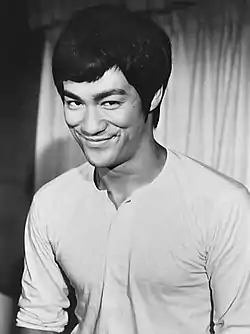 photo en noir et blanc d'un asiatique (Bruce Lee) souriant