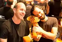 Bruce Straley (à gauche) et Neil Druckmann (à droite) tenant une girafe en peluche, tous deux souriant, lors des PAX Prime 2014.
