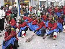 photo montrant des personnes déguisées en sorcières avec masques et balais défilant dans les rues