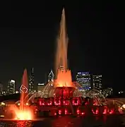 La fontaine illuminée en orange et en rose.