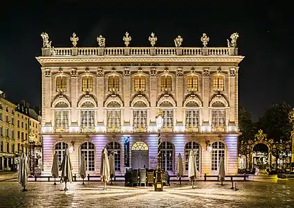 Photographie en couleurs d’une façade ancienne sous éclairage nocturne.